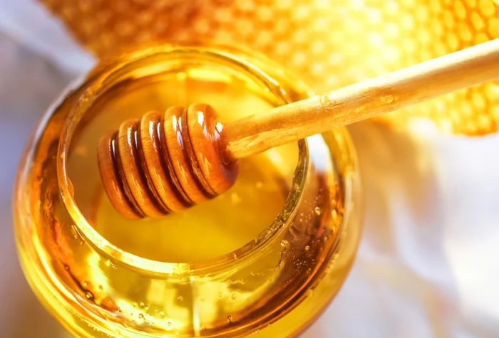 Glas mit goldenen Honig und ein hölzerner Honiglöffel