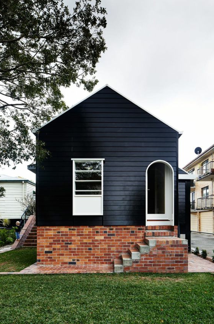 ein kleines Holzhaus im minimalistischen Stil, gestrichen in Schwarz, Ziegelbau, Treppen, minimalistische Architektur