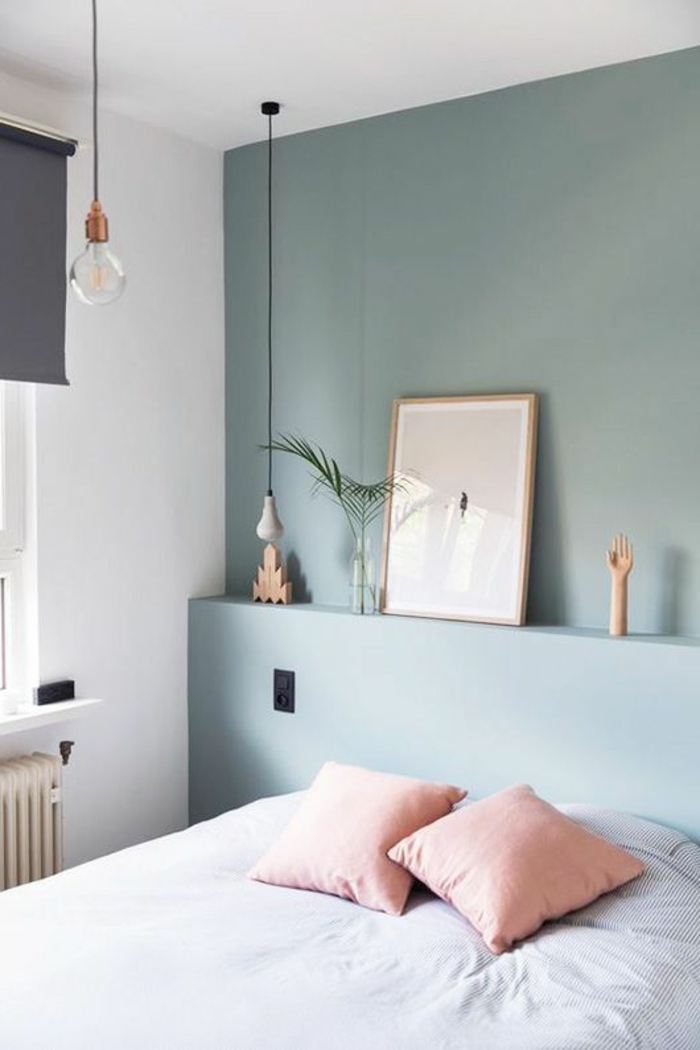 Minimalismus im Schlafzimmer: blaue Wand, Wandregal, Dekos, hellpinke Kissen, weiße Bettwäsche