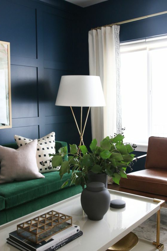 Wandverkleidung aus Holz, gestrichen in Blau, Stehlampe, grüne Polstercouch, Pflanzen, Ledersessel