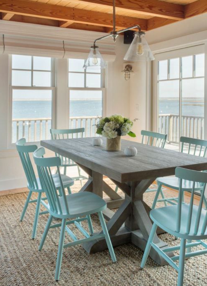 minimalistisches Esszimmer mit Meeresaussicht, Esstisch aus massivem Holz, blaue Holzstühle, Tischdeko