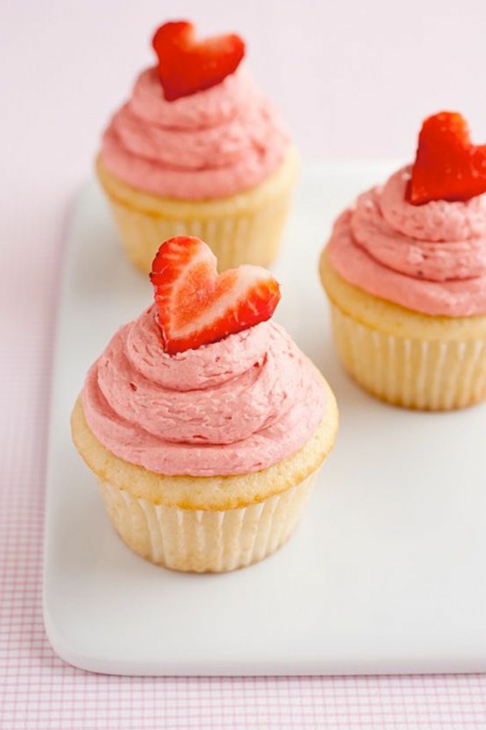 muffins dekoriert mit rosa sahne und herzen aus erdbeeren