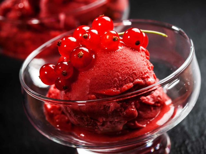 Rhabarber Eis mit roten Beeren, serviert in einem eleganten Dessertglas