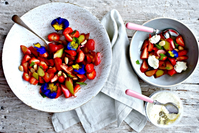Rhabarbersalat mit Erdbeeren, Veilchen und Mascarpone Creme in eleganten Schüsseln aus Porzellan