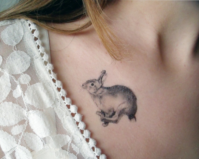tattoos motive kleine hase springt auf dem schulter einer frau blonde haare spitze bluse dekoration