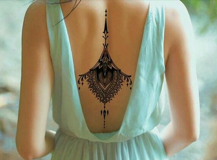 tattoo motive rücken mit schwarzem tattoo dekorieren frau mit schönem blauen kleid offener rücken