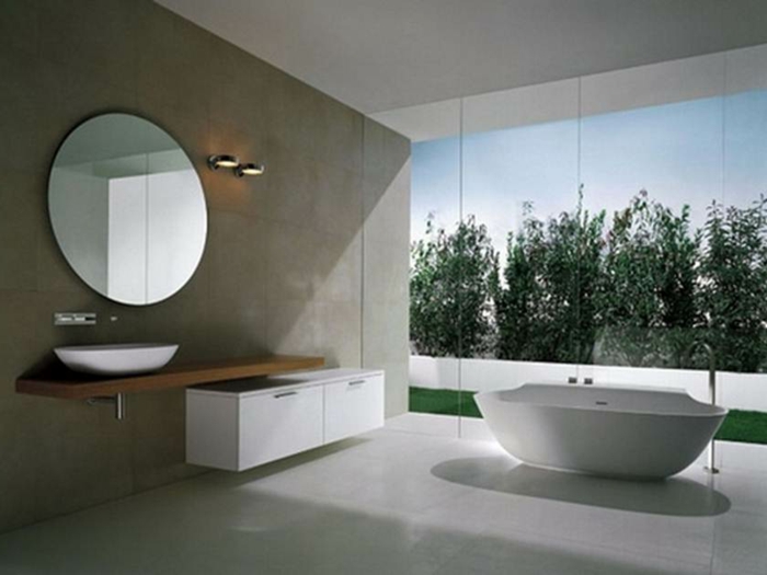 Badezimmer mit rundem Spiegel, Schrank in weißer Farbe und weiße ovale Badewanne, Waldaussicht