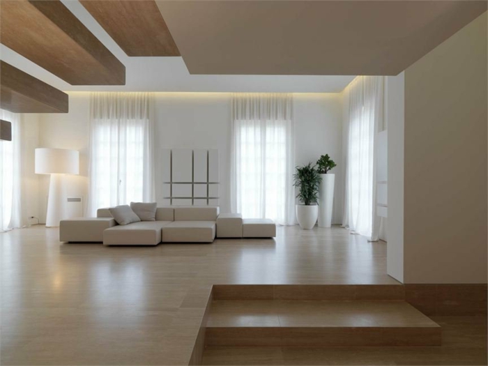 Wohnzimmer in Naturfarben mit weißer Couch, zwei Pflanzen, Designer-Stehlampe und Laminatboden