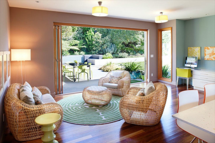 ein großes Wohnzimmer mit rundem Musterteppich in türkisgrün und weiß, großer Garten