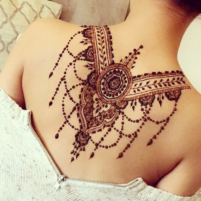 rötliche temporäre Tätowierung mit Henna Farbe am Rücken einer Frau unter dem Hals, Punktentattoo