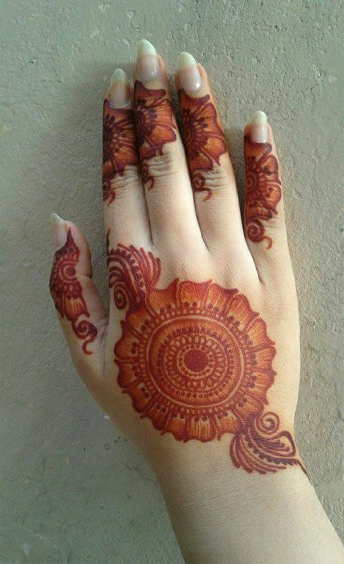 temporäre rote Henna Tätowierung auf der Handoberfläche einer Frau mit langen Nägeln, Blumentattoos