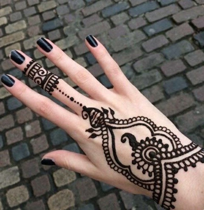 Frau mit Henna Tattoo auf der Hand und auf dem Mittelfinger in schwarz, schwarzer Nagellack