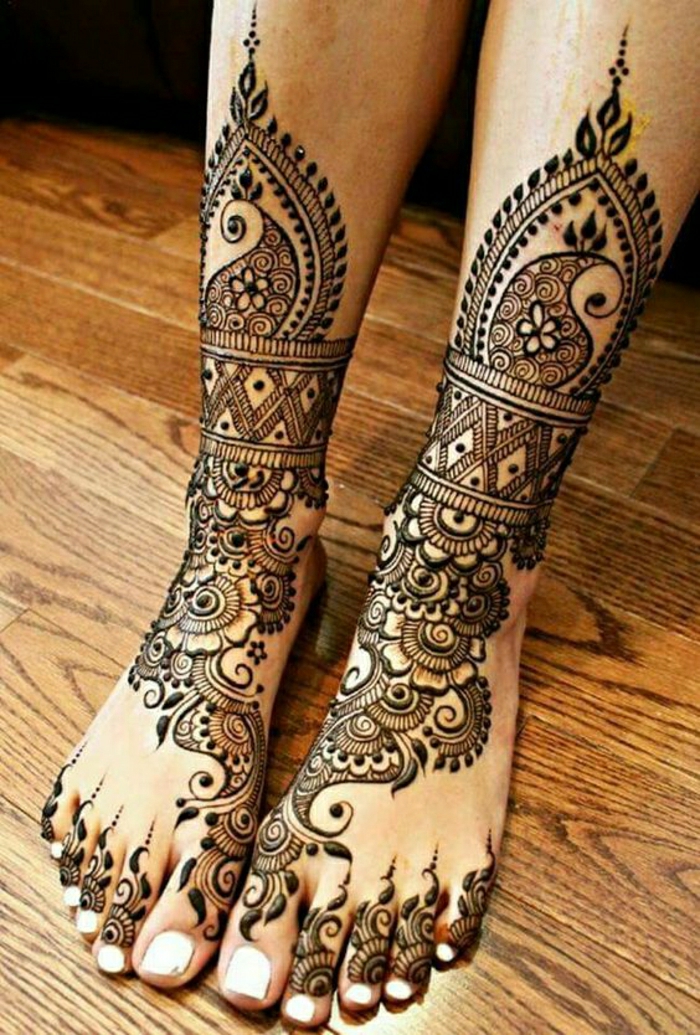 Frau mit tätowierten Beinen, Knöcheln und Zehen mit Hennafarbe, viele Ornamente, weißer Nagellack