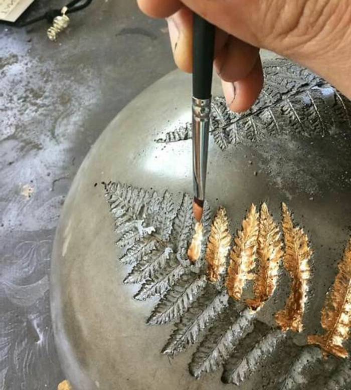 diy deko aus zement - kugel mit goldener farbe verzieren, pinsel, baumblätter