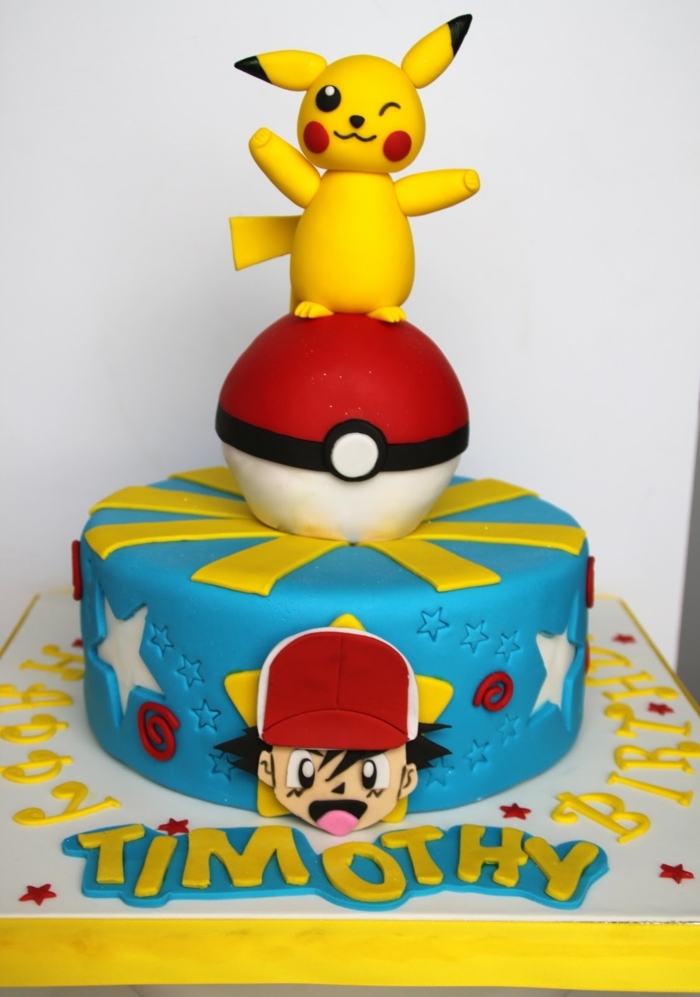 idee für eine blaue pokemon torte - ein kleines pokemon wesen pikachu mit schwarzen augen und roten backen und ein roter pokeball und ein junge mit mütze
