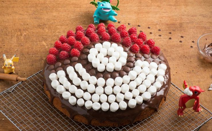 eine tolle schoko pokemon torte mit weißem pralinen und roten himbeeren und drei kleinen pokemon wesen und pikachu
