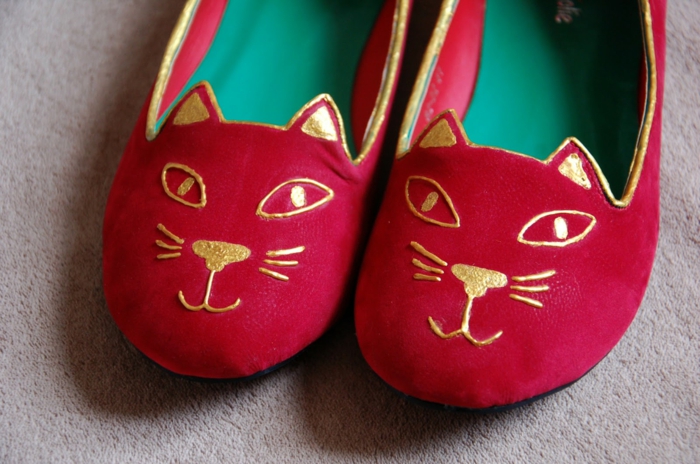 rote Schuhe nähen mit einer goldenen Verzierung wie eine Katze Miene