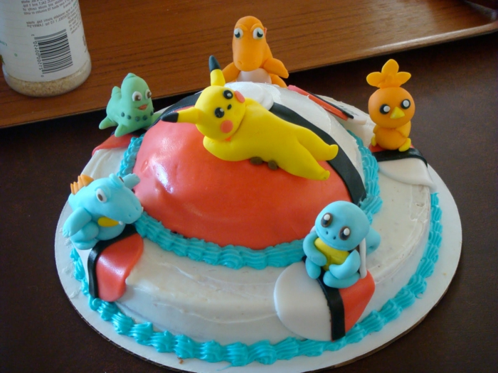 ein roter pokeball und sechs kleine pokemon wesen, ein pikachu - eine idee für eine pokemon torte mit einer blauen creme 