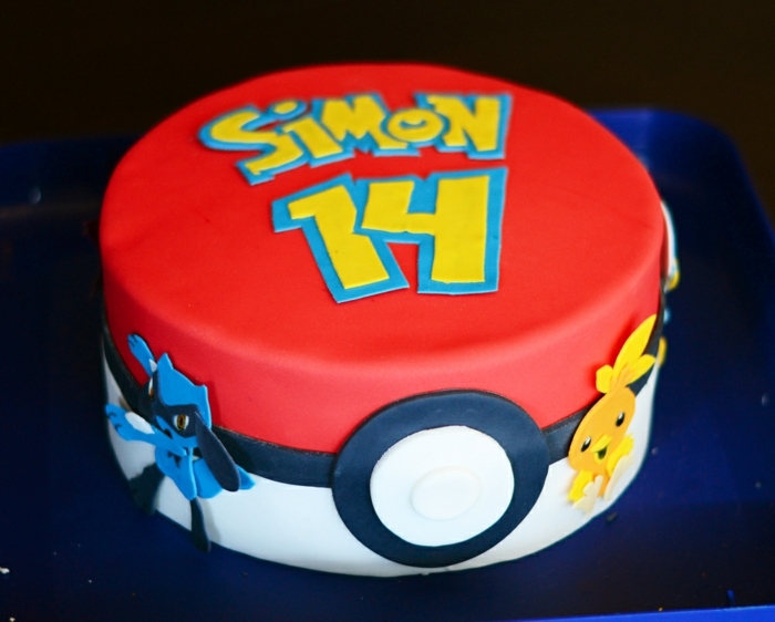 pokemon birthday cake - eine idee für eine große rote pokemon torte, die wie ein roter pokeball ausieht, mit gelben überschriften und zwei kleine pokemon wesen