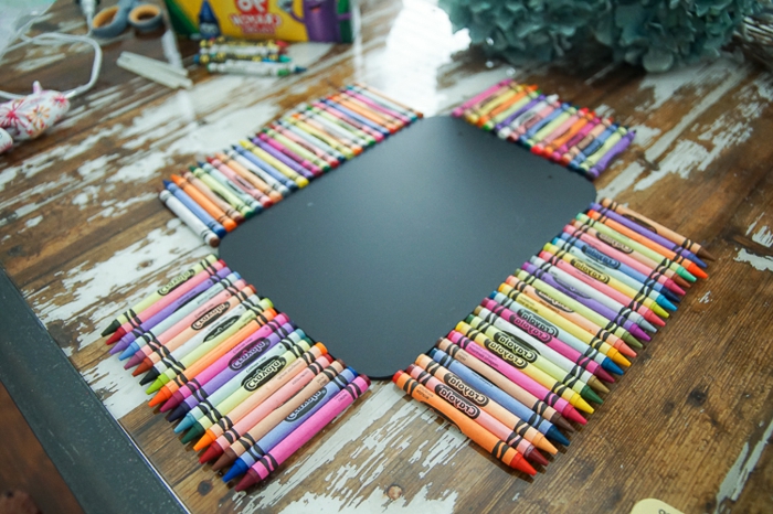 Süße Schulsachen - Buntstiften in Farben wie Regenbogen umgeben eine schwarze Tafel