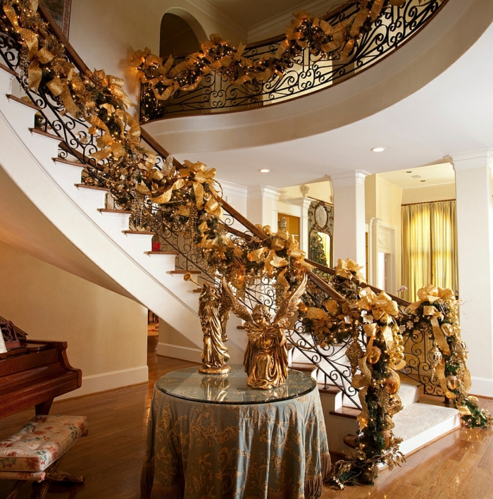 goldene Dekoration von Treppenaufgang zu Weihnachten mit Bänden, Lichterkette und Engel auf dem Tisch