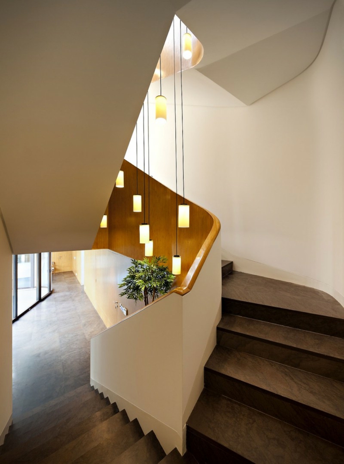 braune Treppe mit weißem Geländer und hängende Lampen, grüne Pflanze