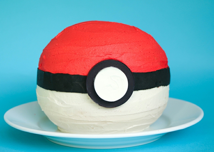 hier ist ein weißer teller und eine rote pokemon torte - diese torte sieht wie ein roter pokeball aus 
