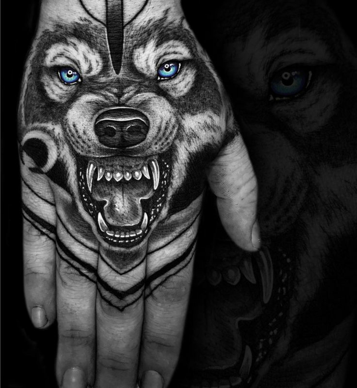 hier ist ein schwarzer zähnefletschender wolf mit schönen blauen augen - idee für einen wolf tattoo auf hand 