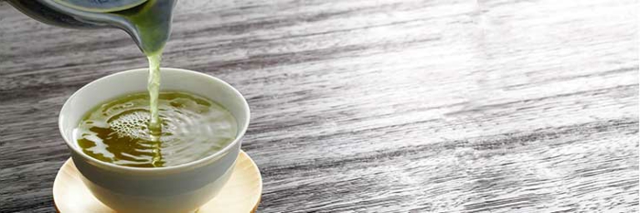 gesunde Ernährung, richtige Ernährung, grüner Tee in einer weißen Tasse auf einem Holztisch