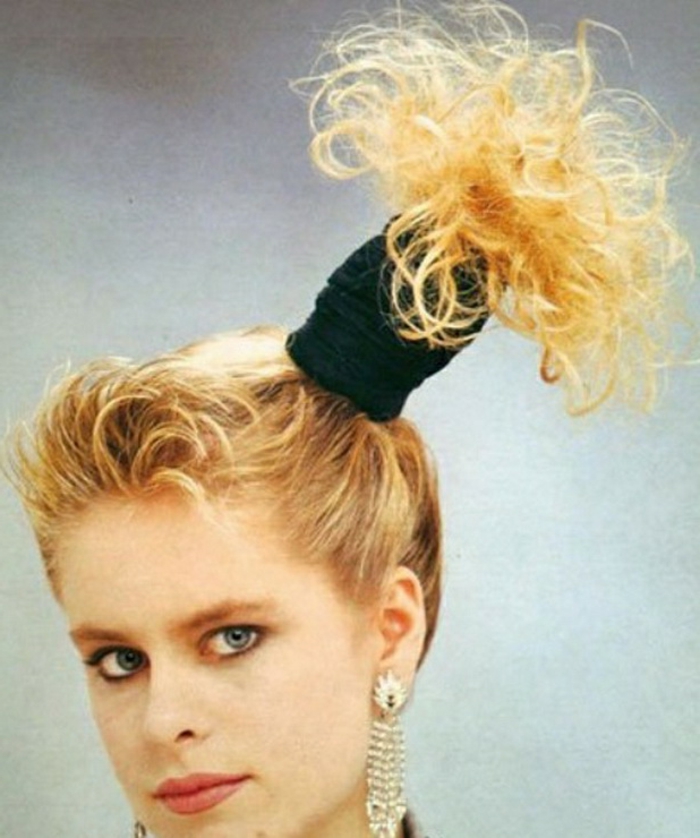 eine Frau mit Seitenschwanz, schwarzes Haarband, schwarzes Schwitzband, riesige goldene Ohrringe