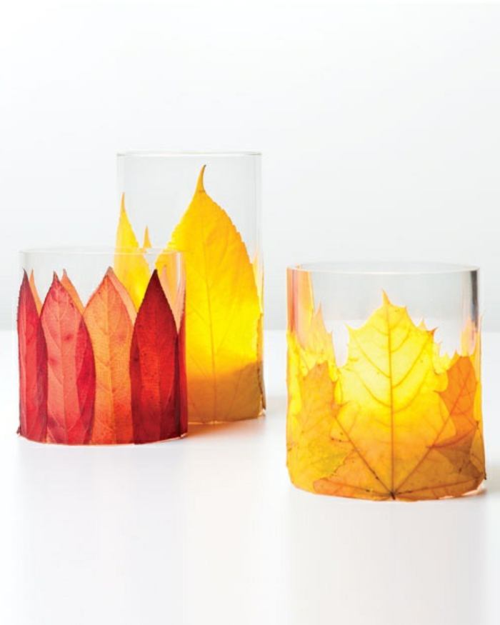 kerzenhalter aus glas dekoriert mit herbstblättern in verschiedenen farben
