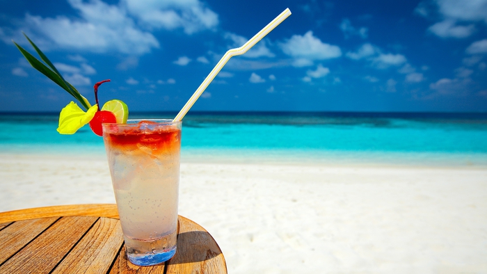 Cocktail mit Zitrusfrüchten, das Meer als Hintergrund, ein erfrischendes Getränk und die Sonne genießen