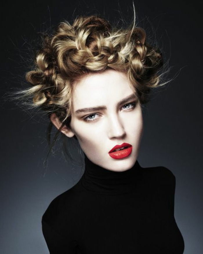 junge Frau mit weißer Haut und blonden Haaren mit einer Flechtfrisur, schwarze Polobluse, roter Lippenstift