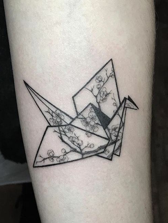 hier finden sie eine idee zum thema origami tattoo - ein fliegender schwarzer origami vogel mit kleinen weißen blumen 