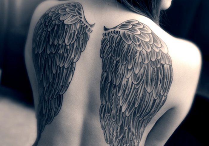 hier ist eine frau mit einem großen engel tattoo mit langen schwarzen engelsflügeln 