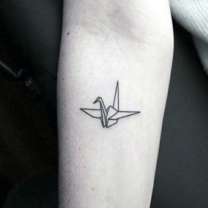 bilder zum thema origami tattoo - hier ist eine schwarze tätowierung mit einem kleinen fliegenden origami vogel 