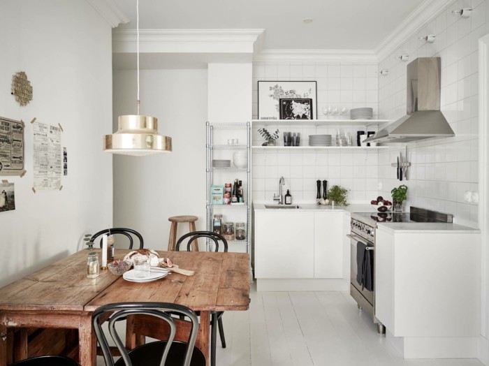 Küche mit ausziehbarem Esstisch aus Massivholz, weiße Fliesenwand, eingebaute Küchenregale