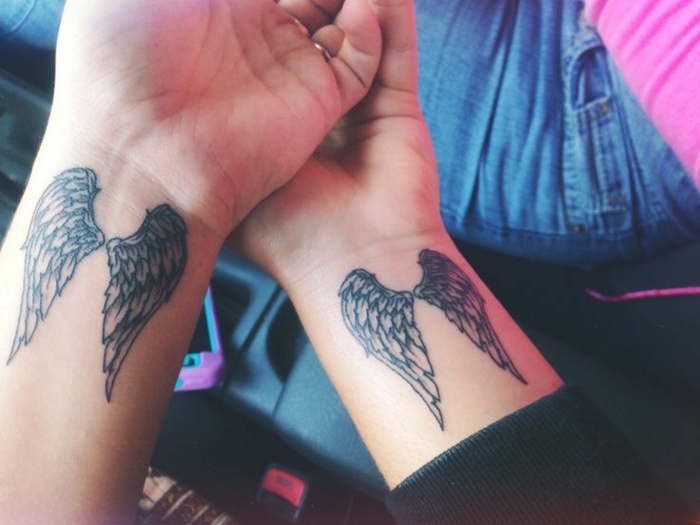 noch einige ideen für kleine engel tattoos - hier sind zwei hände mit kleinen engelsflügel tattoos mit langen schwarzen federn 