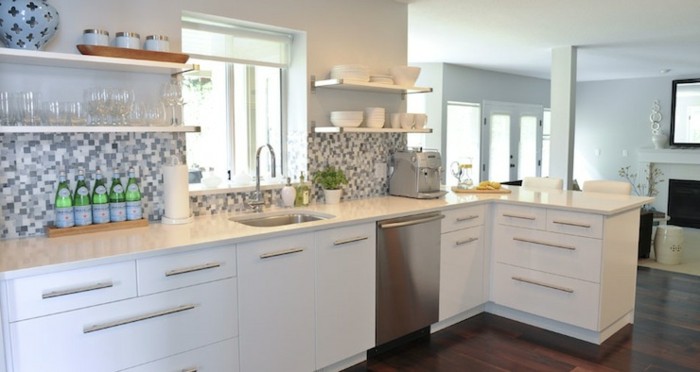 L-Küche mit Laminatboden, Mosaik-Küchenrückwand in grauen Nuancen, Fenster vor dem Waschbecken