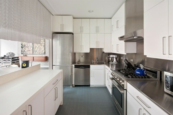 Küche mit kleinen schwarzen Bodenfliesen, weiße Küchenschränke mit Standardgriffen aus Metall
