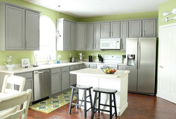 Wanddeko Besteck, grüne Wände, graue Schranken, weiße Kochinsel, Musterteppich in der Küche
