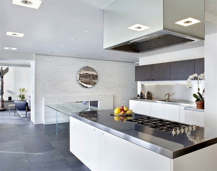 Küche mit Marmorwand, Glastisch, riesengroße Abzugshaube, Wanddeko aus Metall, Spiegel