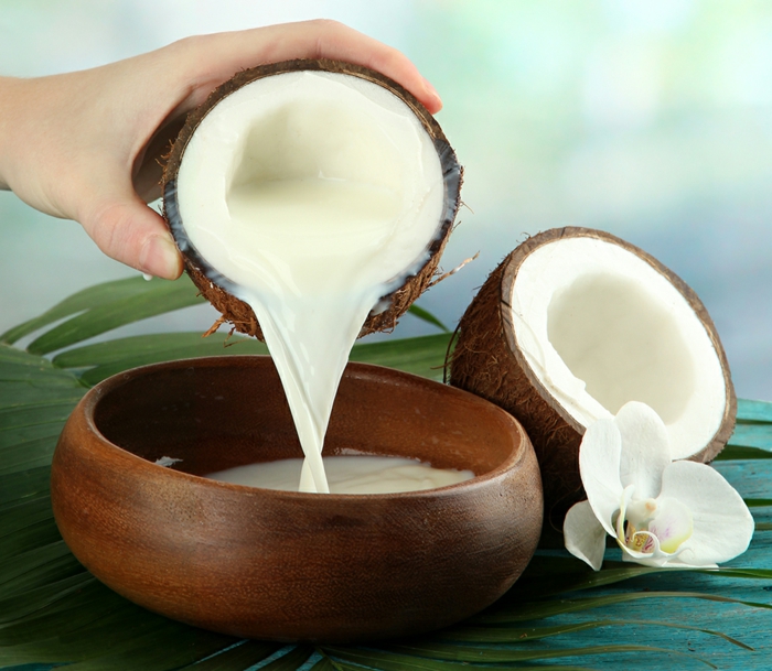 die Kokosmilch ist als ein natürliches Haarwuchsmittel bekannt, Kokosnuss, Holzschüssel, weiße Orchidee