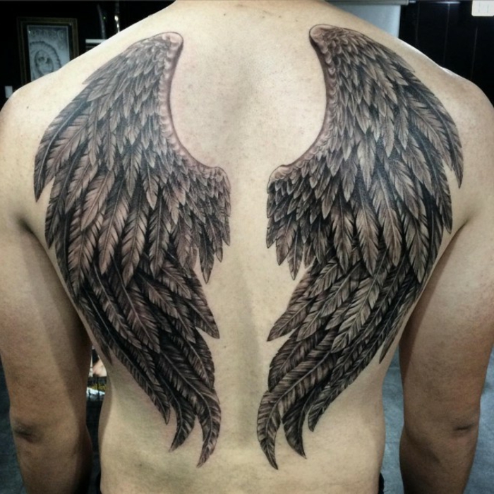 ein man und sein engel tattoo mit zwei schwarzen engelsflügeln mit langen schwarzen federn 