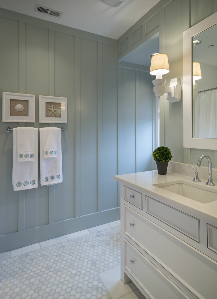 maritime Badezimmer, blass blaue Wand mit Bilder von Muschel und Seestern, weißer Waschbecken mit Schränken, weiße Handtücher, 