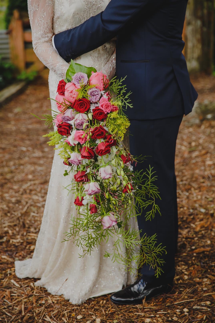 Hochzeitsstrauß vintage länglicher Strauß mit roten und lila Rosen und viele grüne Pflanzen