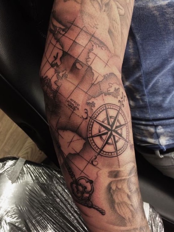 die welt und eun großer kompass - idee für einen sehr schönen compass tattoo auf der hand 