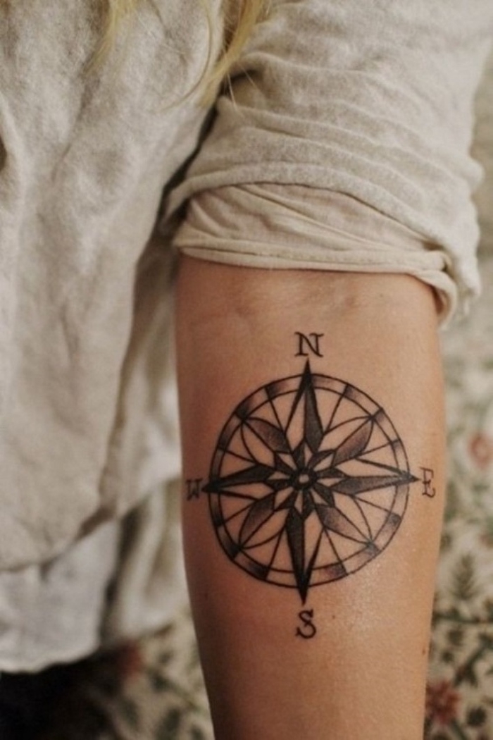 eine frau mit einer schwarzen kleinen tätowierung mit einem schwarzen kompass - idee für einen tattoo auf hand