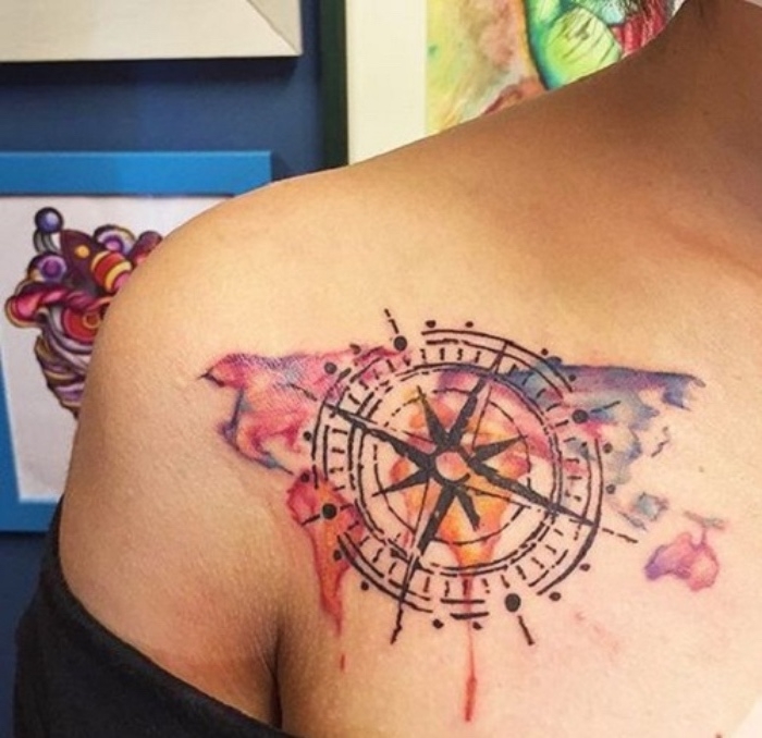eine bunte weltkarte und ein großer schwarzer kompass - idee für einen compass tattoo auf dem schulter