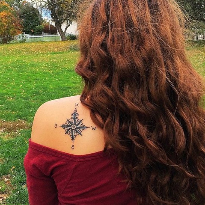 eine junge frau mit einem tollen compass tattoo auf ihrem schulterblatt - eine schwarze tätowierung mit einem schwarzen kompass